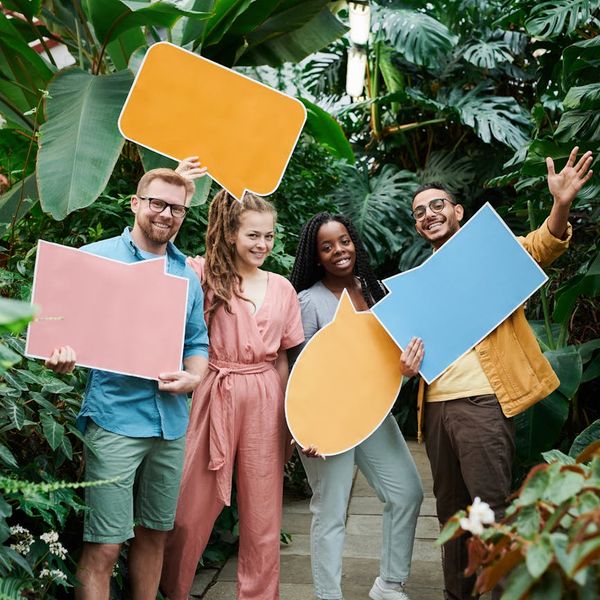 Diverse group of people smiling and looking relaxed outdoors.